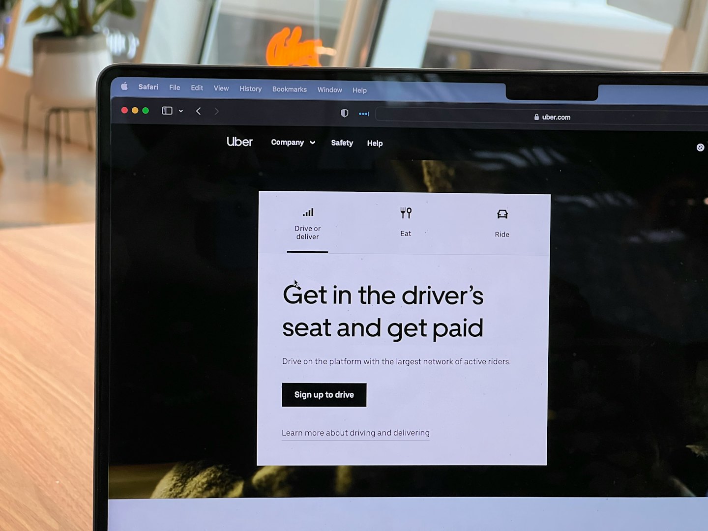Nešiojamojo kompiuterio ekrane rodoma „Uber“ registracijos svetainė ant stalo.